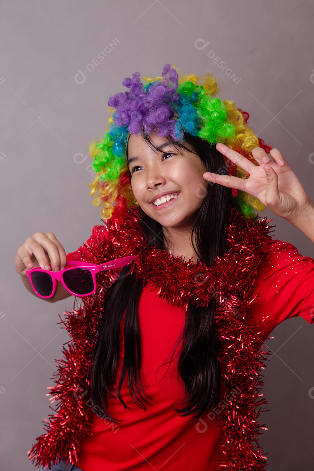 Criança japonesa com peruca colorida e óculos escuro e roupa vermelha em fundo cinza