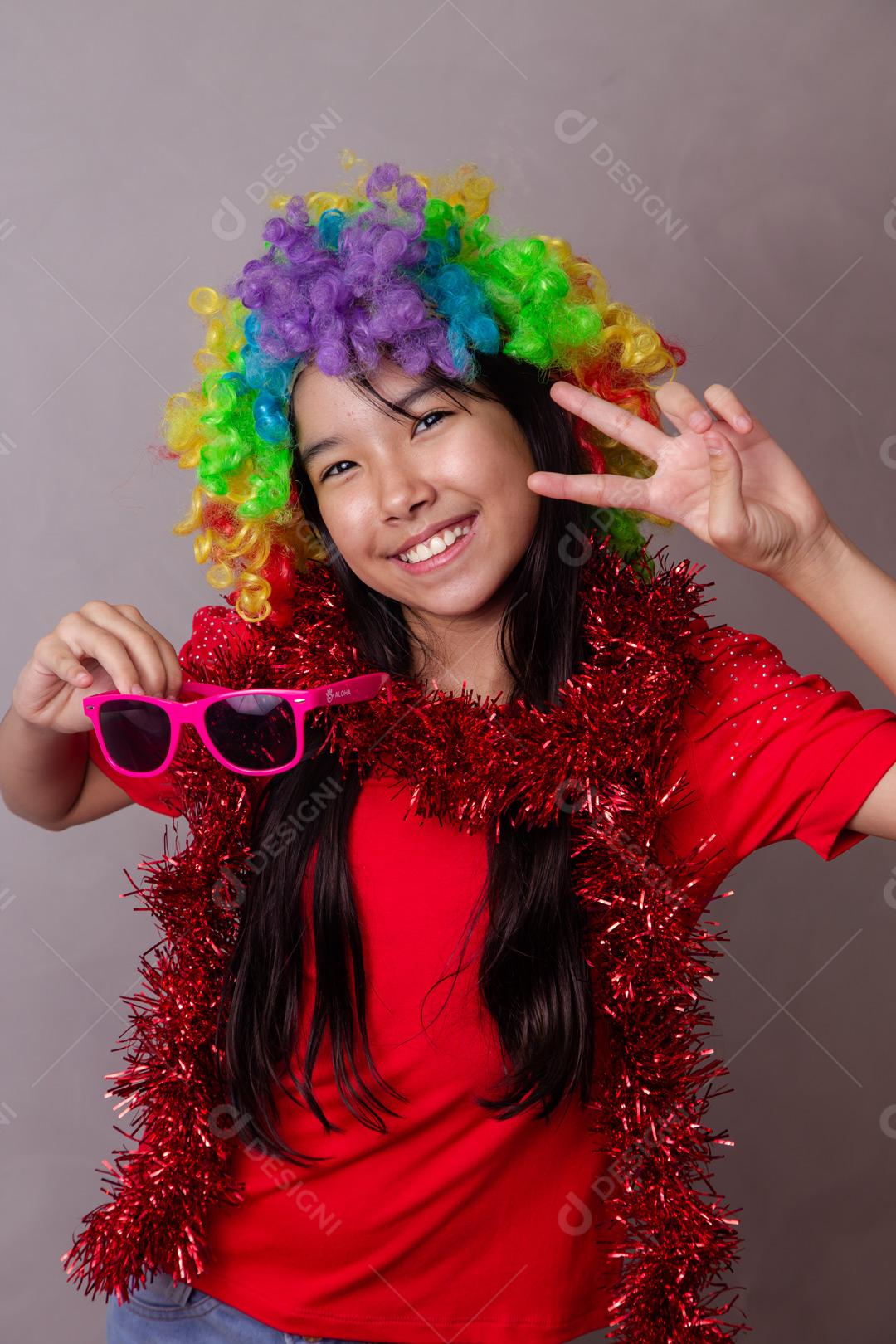 Criança japonesa com peruca colorida e óculos escuro e roupa vermelha em fundo cinza