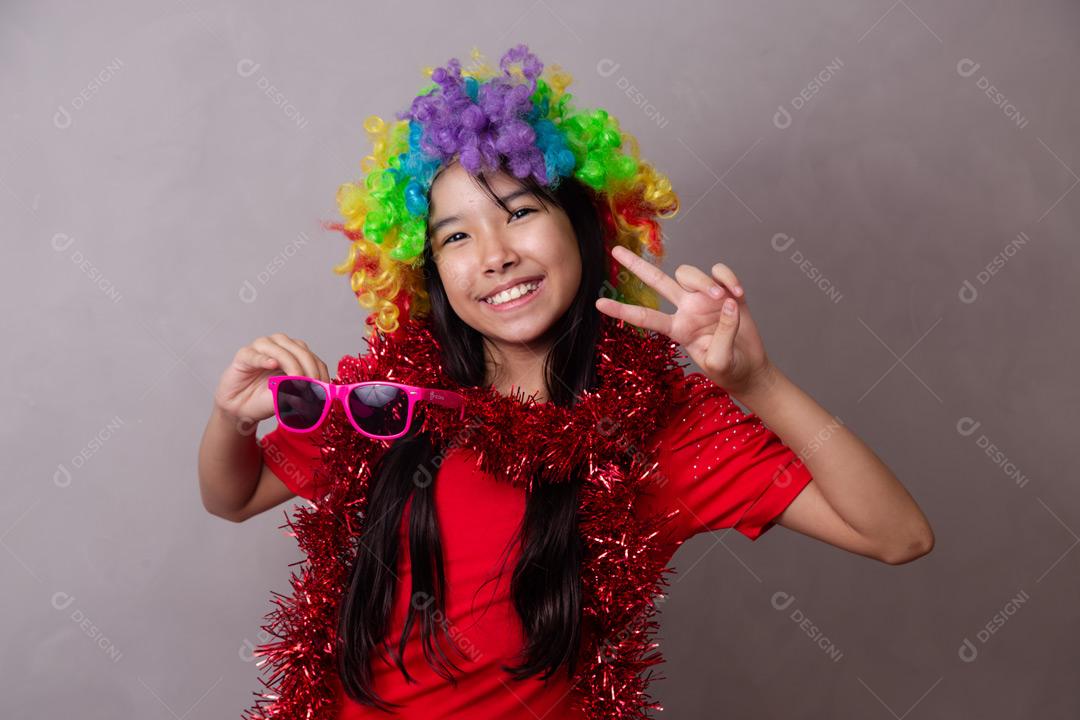 Criança japonesa com peruca colorida e óculos escuro e roupa vermelha em fundo cinza