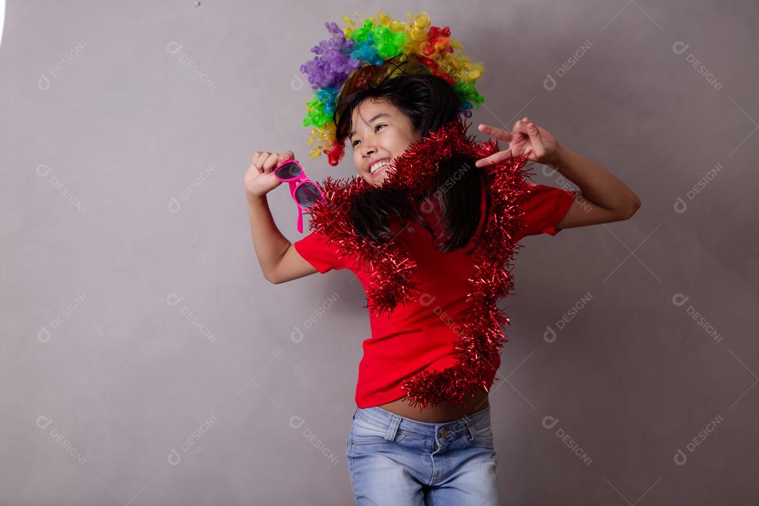 Criança japonesa com peruca colorida e óculos escuro e roupa vermelha em fundo cinza