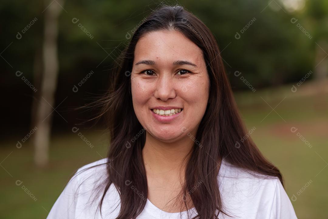 Mulher asiática sorridente feliz olhando para a câmera sobre fundo verde. Mulher japonesa no parque sorrindo