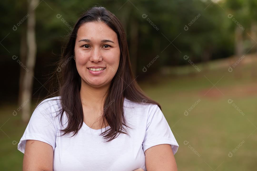 Mulher asiática sorridente feliz olhando para a câmera sobre fundo verde. Mulher japonesa no parque sorrindo