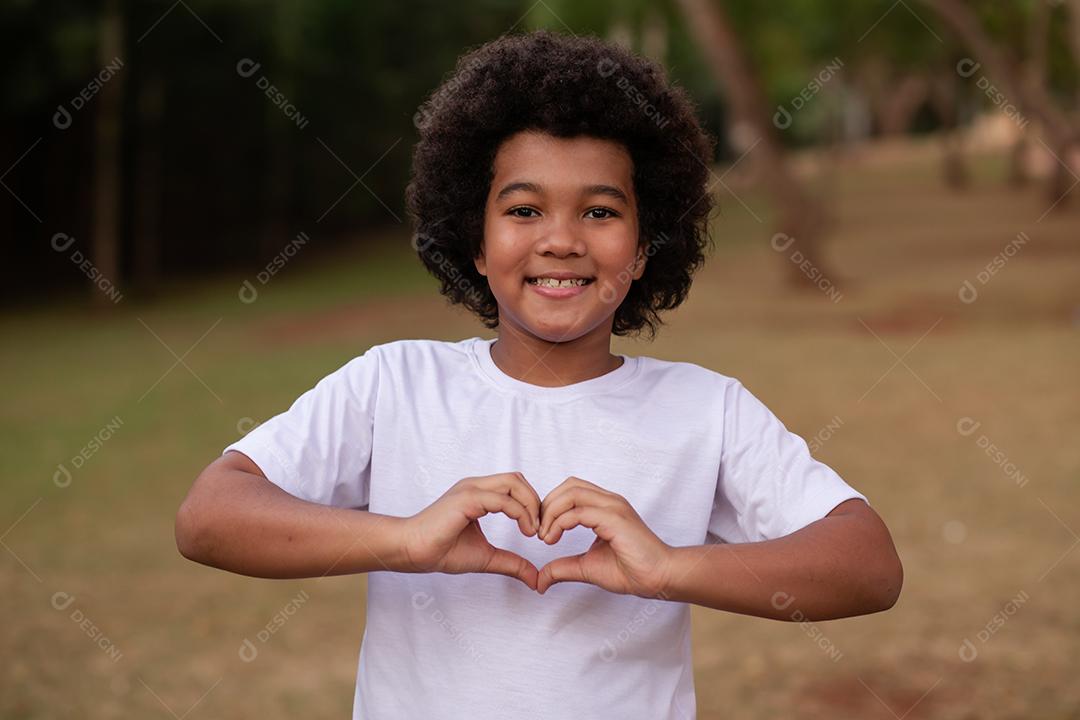 Menino Afro fazendo coração com a mão