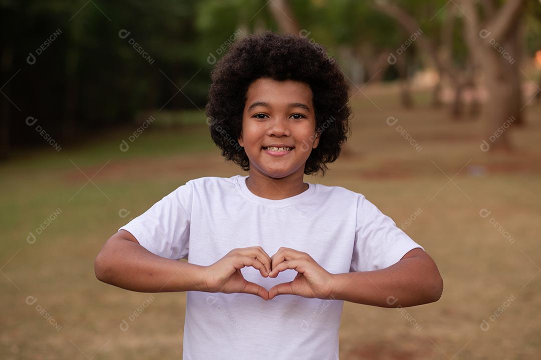 Menino Afro fazendo coração com a mão