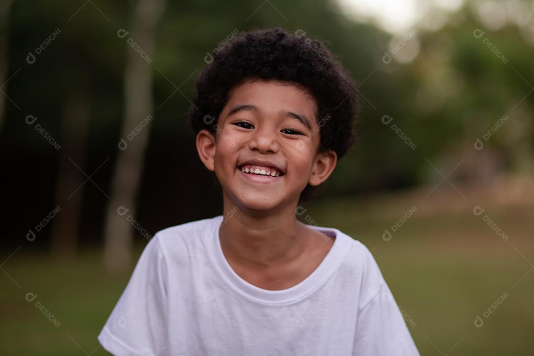 menino afro sorrindo para a câmera no parque