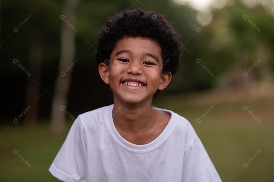 menino afro sorrindo para a câmera no parque