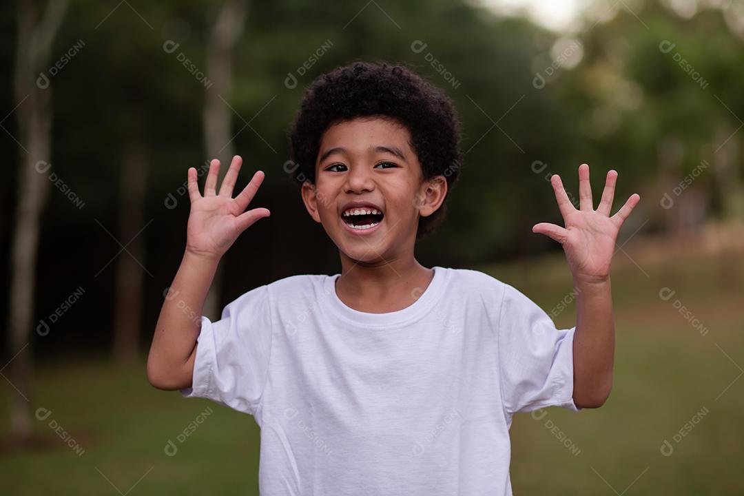 menino afro fazendo careta mostrando as mãos para a câmera