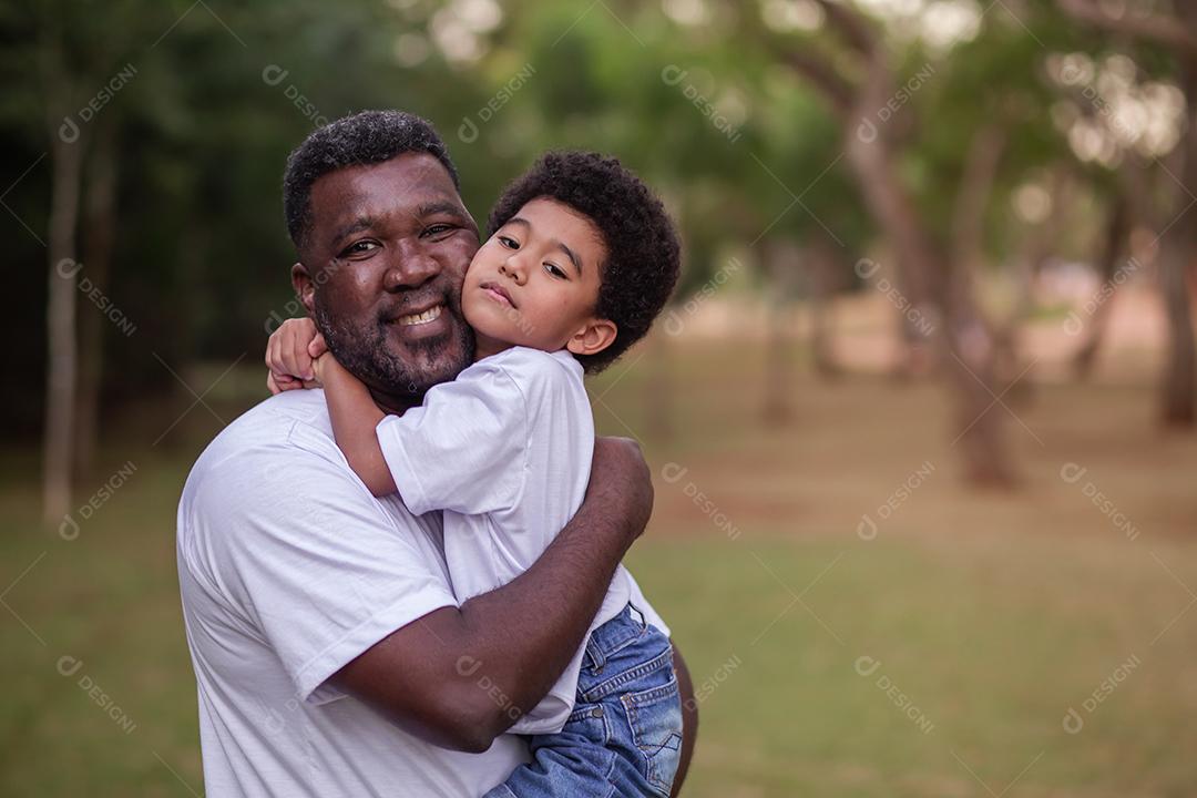 Pai e filho afro abraçados no parque. Dia dos Pais.