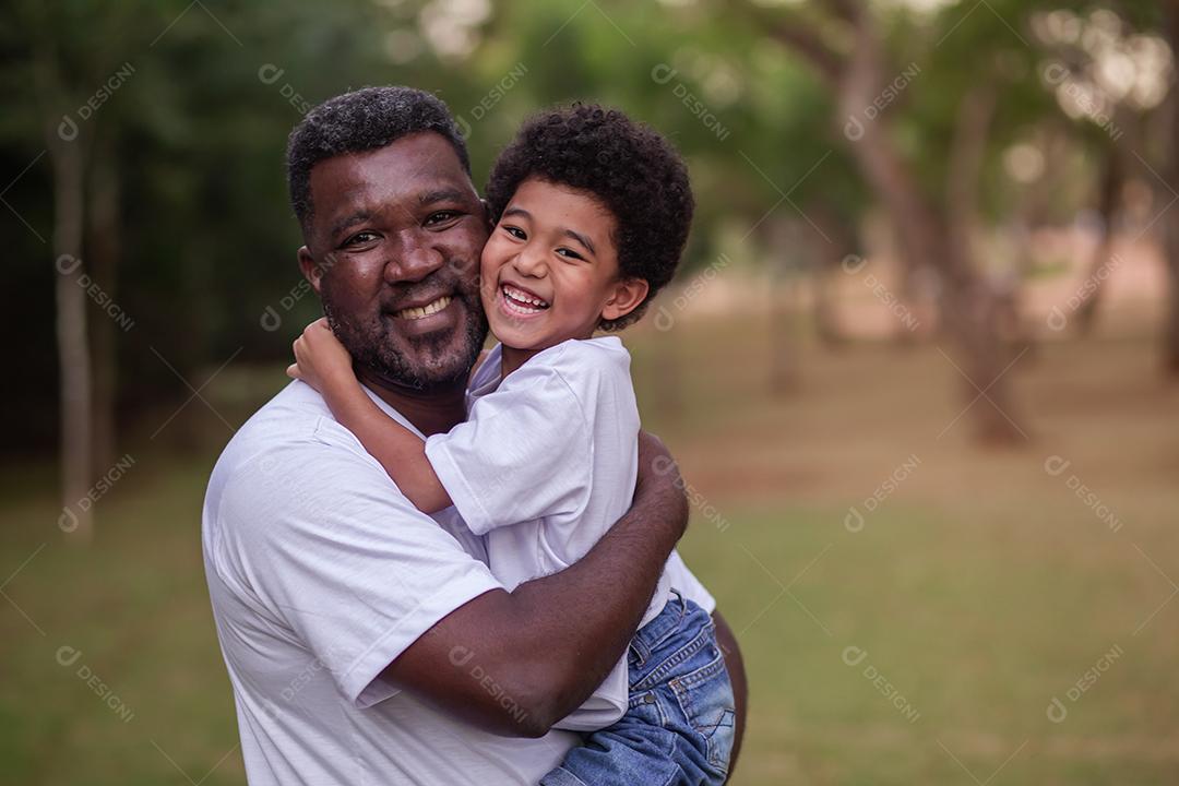 Pai e filho afro abraçados no parque. Dia dos Pais.