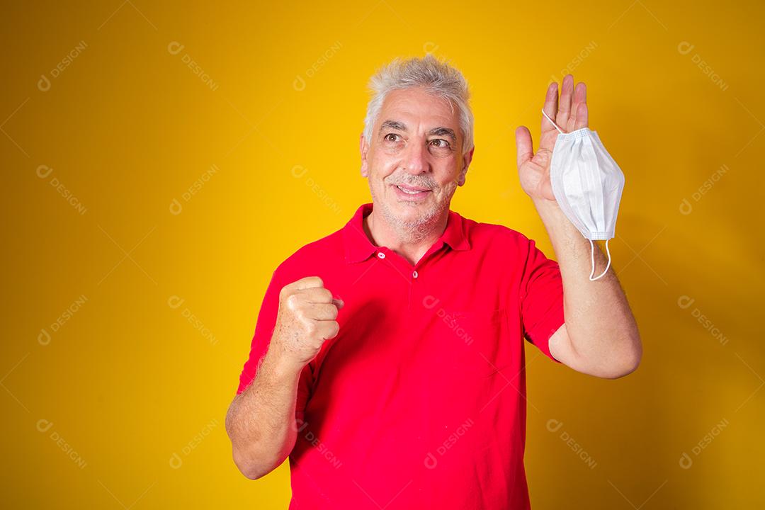 homem idoso segurando a máscara na mão