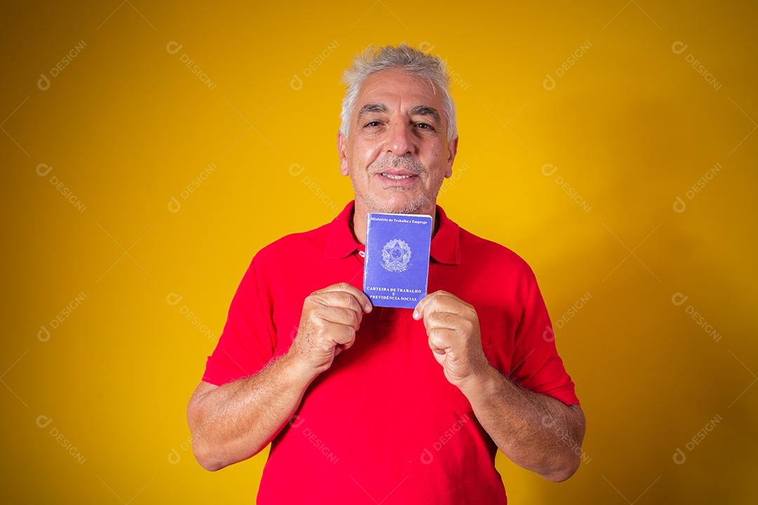homem idoso segurando um cartão de trabalho brasileiro