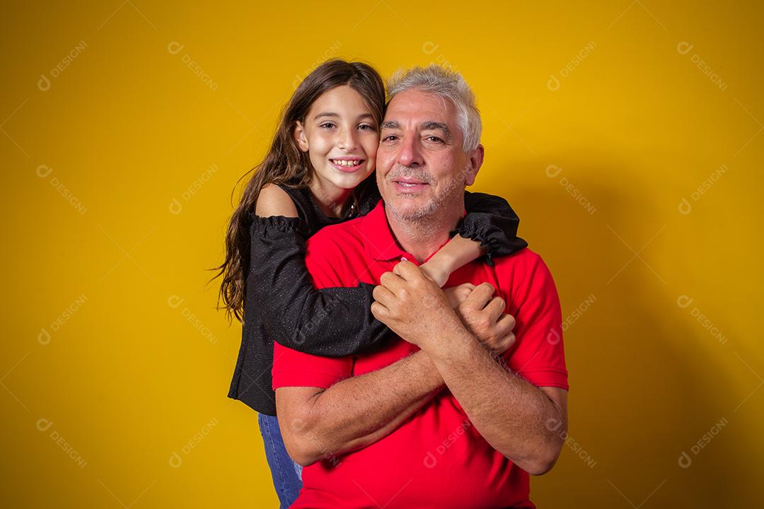 Menina linda criança com seu pai mais velho em fundo amarelo. Dia dos Pais