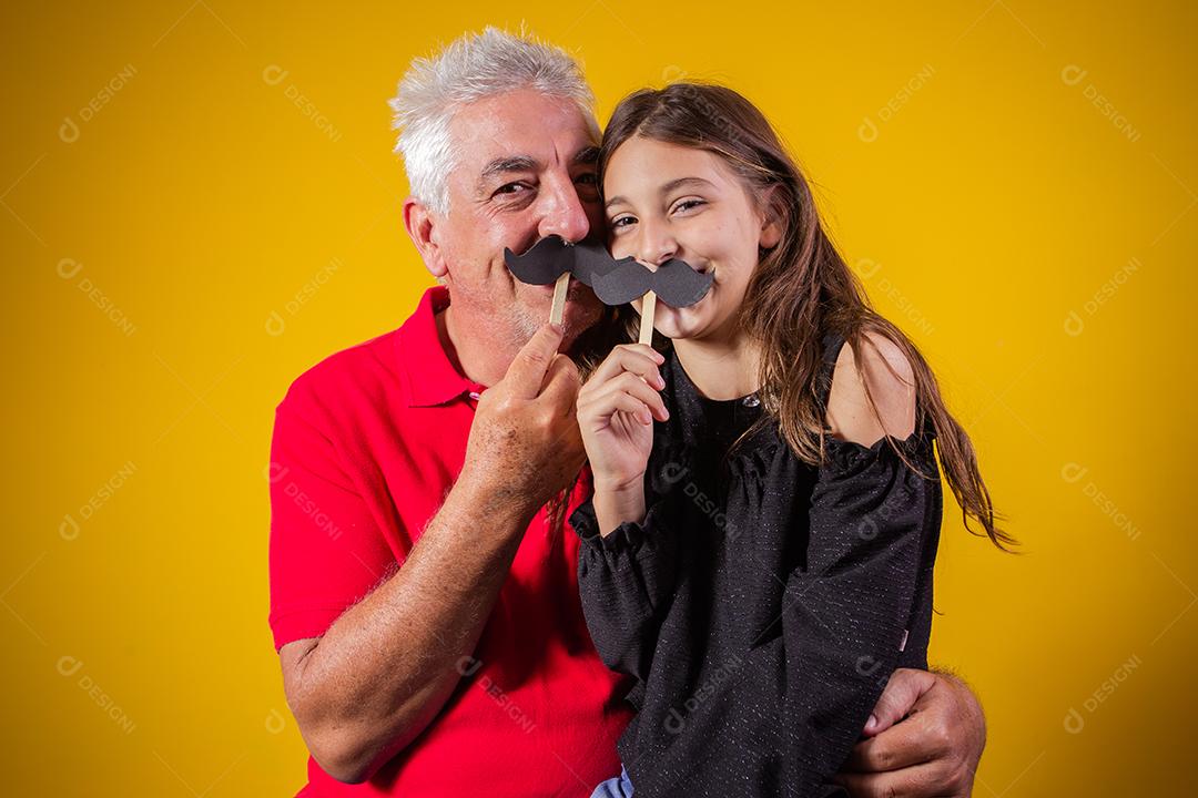 Dia dos Pais. Filha feliz segurando um bigode de papel com o pai em fundo amarelo. filha e pai com bigode de férias