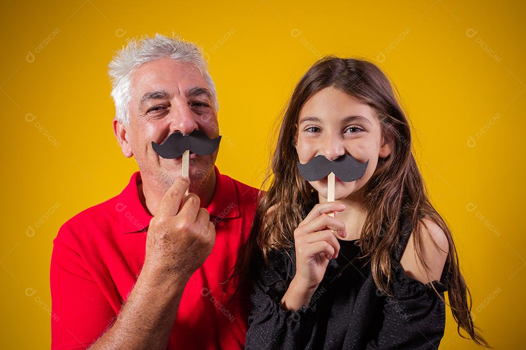 Dia dos Pais. Filha feliz segurando um bigode de papel com o pai em fundo amarelo. filha e pai com bigode de férias
