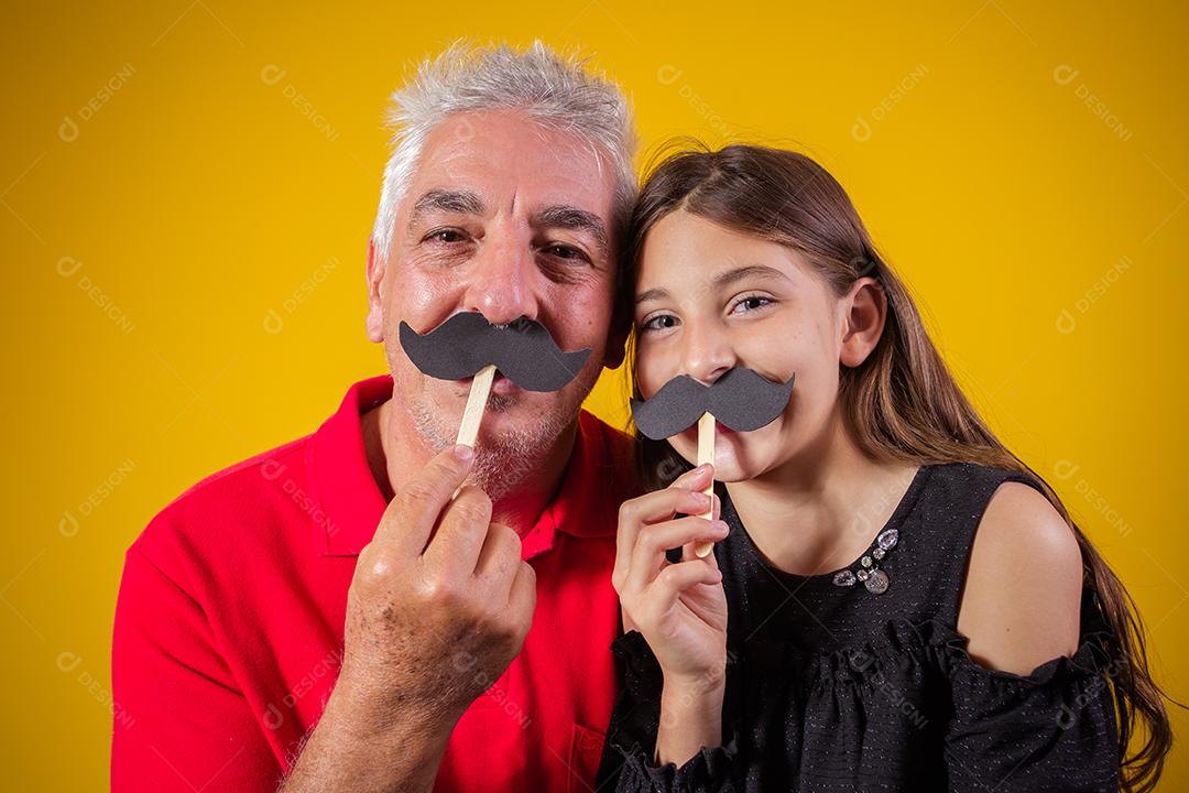 Dia dos Pais. Filha feliz segurando um bigode de papel com o pai em fundo amarelo. filha e pai com bigode de férias