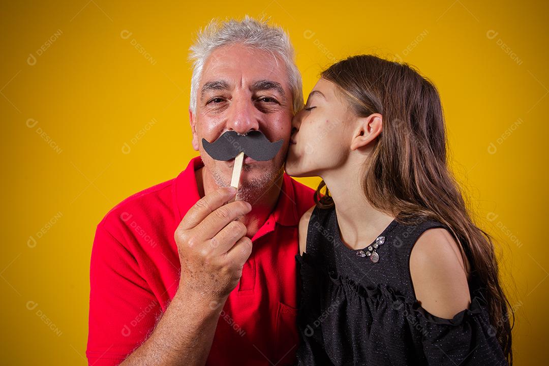 Dia dos Pais. Filha feliz segurando um bigode de papel com o pai em fundo amarelo. filha e pai com bigode de férias