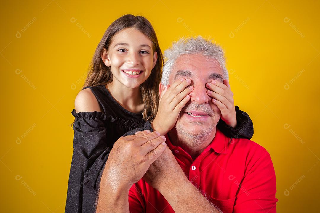 menina segurando o pai fechou os olhos. fundo amarelo. Dia dos Pais. família brasileira.