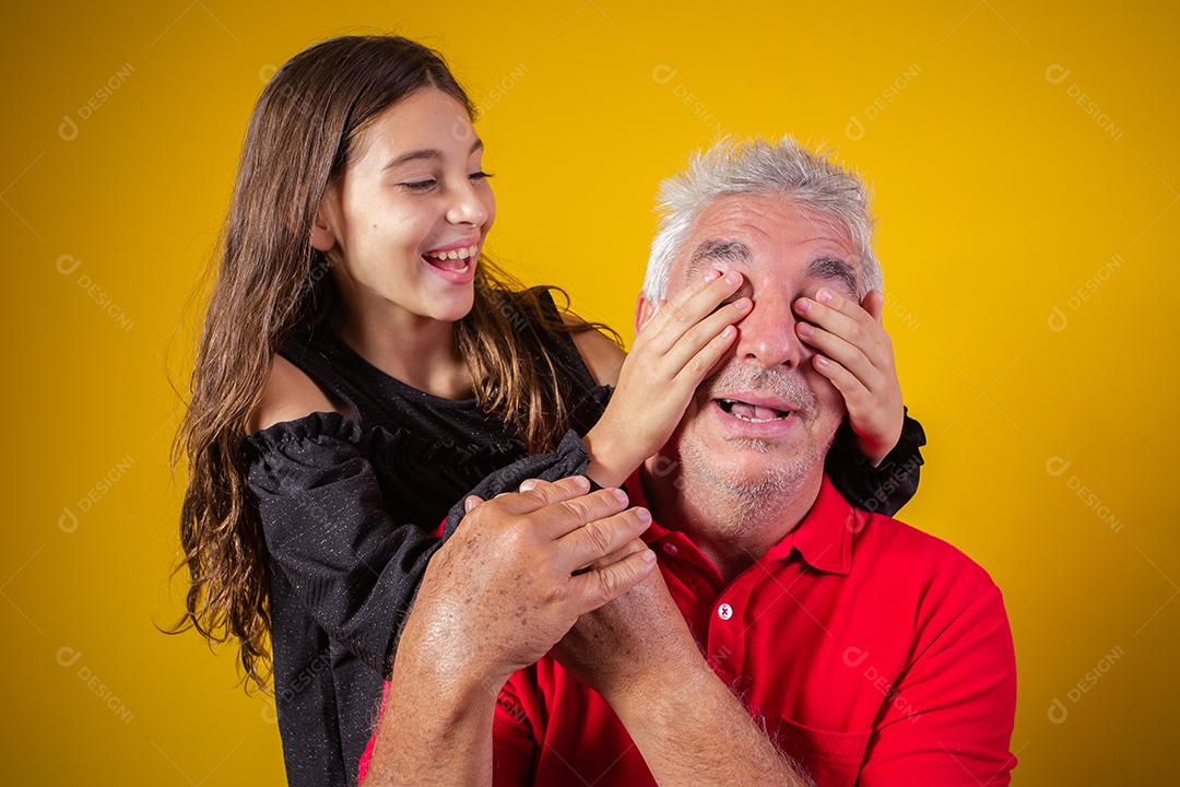 menina segurando o pai fechou os olhos. fundo amarelo. Dia dos Pais. família brasileira.