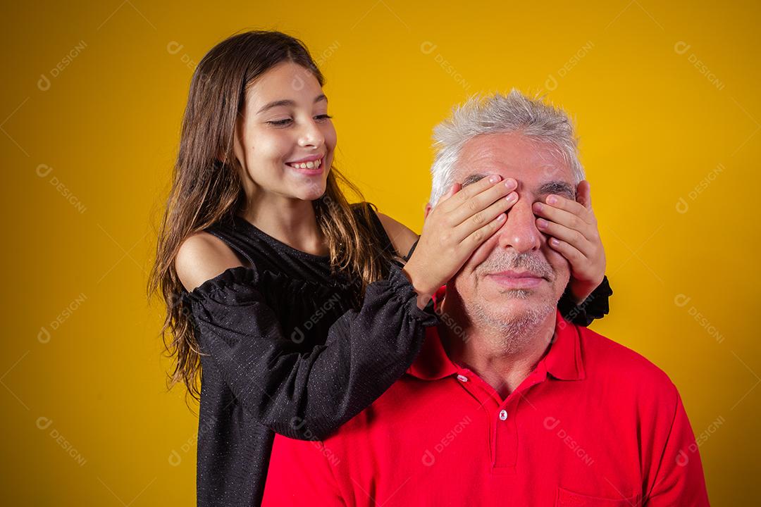 menina segurando o pai fechou os olhos. fundo amarelo. Dia dos Pais. família brasileira.