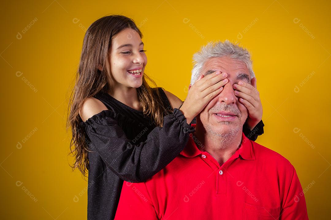 menina segurando o pai fechou os olhos. fundo amarelo. Dia dos Pais. família brasileira.