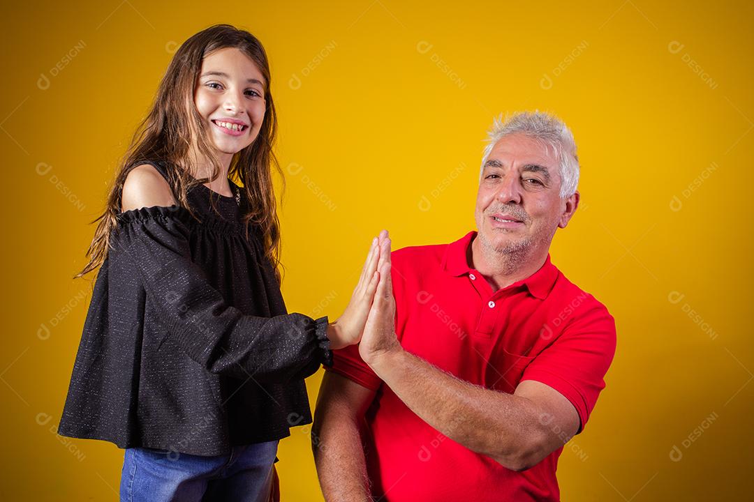 menina segurando o pai fechou os olhos. fundo amarelo. Dia dos Pais. família brasileira.