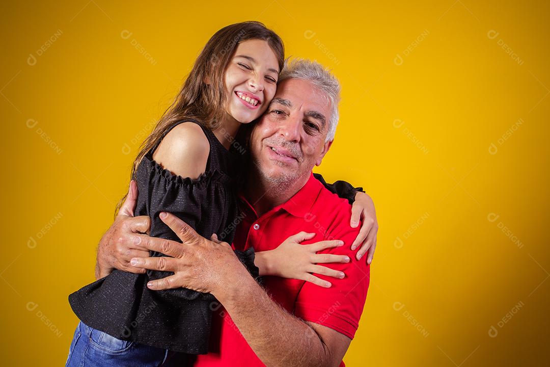 menina criança abraçando o avô dela. Pai e filha em fundo amarelo. Dia dos Pais. dia do avô