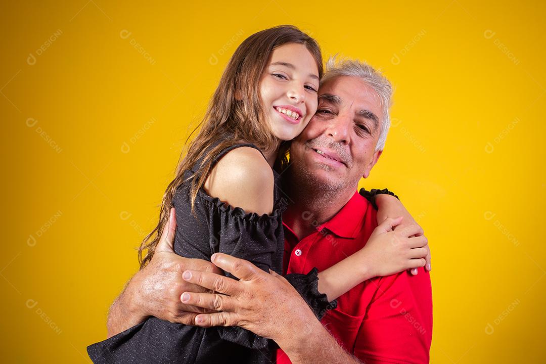 menina criança abraçando o avô dela. Pai e filha em fundo amarelo. Dia dos Pais. dia do avô