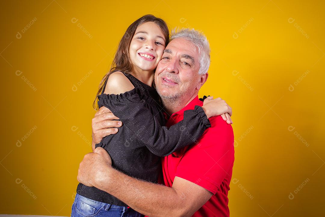 menina criança abraçando o avô dela. Pai e filha em fundo amarelo. Dia dos Pais. dia do avô