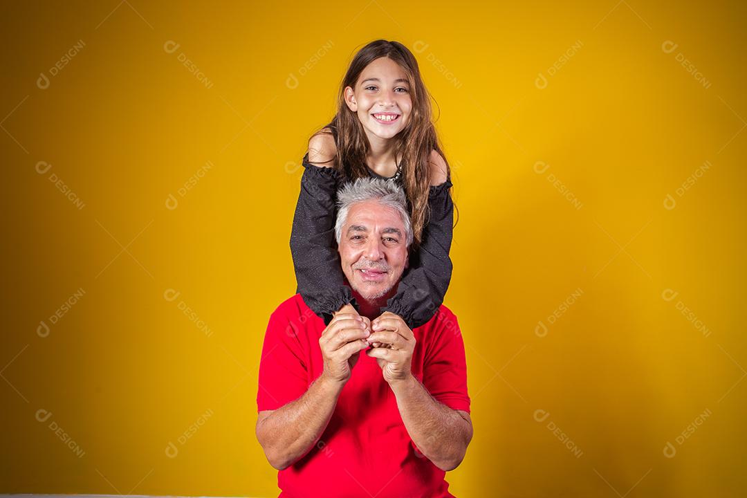 menina criança abraçando o avô dela. Pai e filha em fundo amarelo. Dia dos Pais. dia do avô