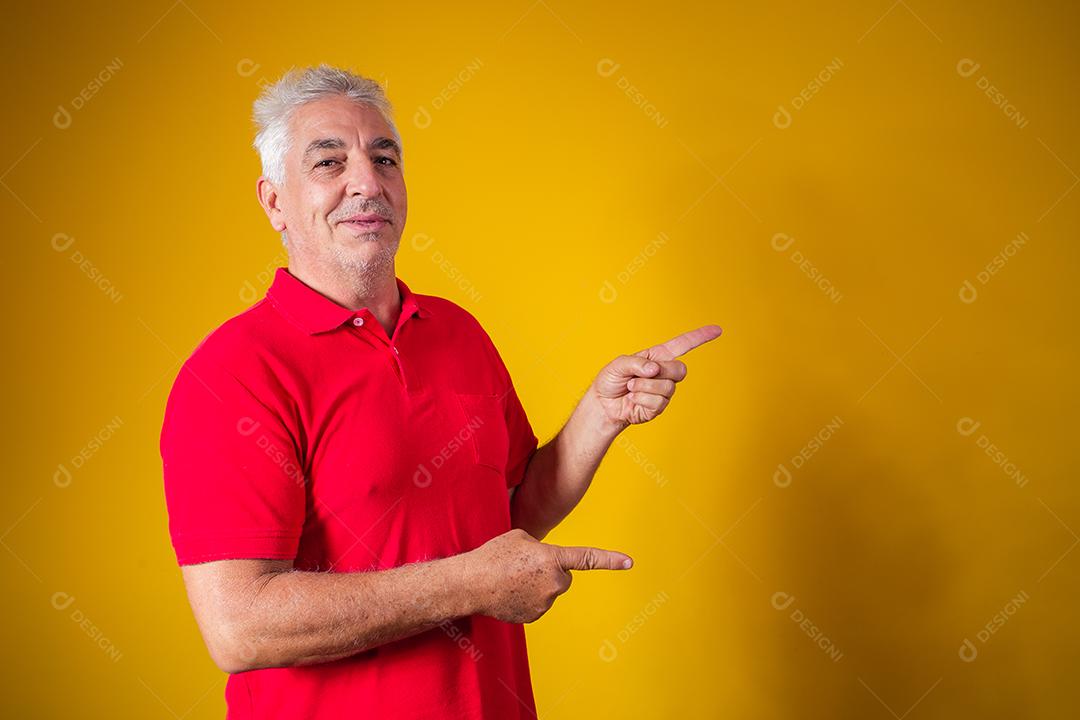 Homem idoso com camisa vermelha em fundo amarelo