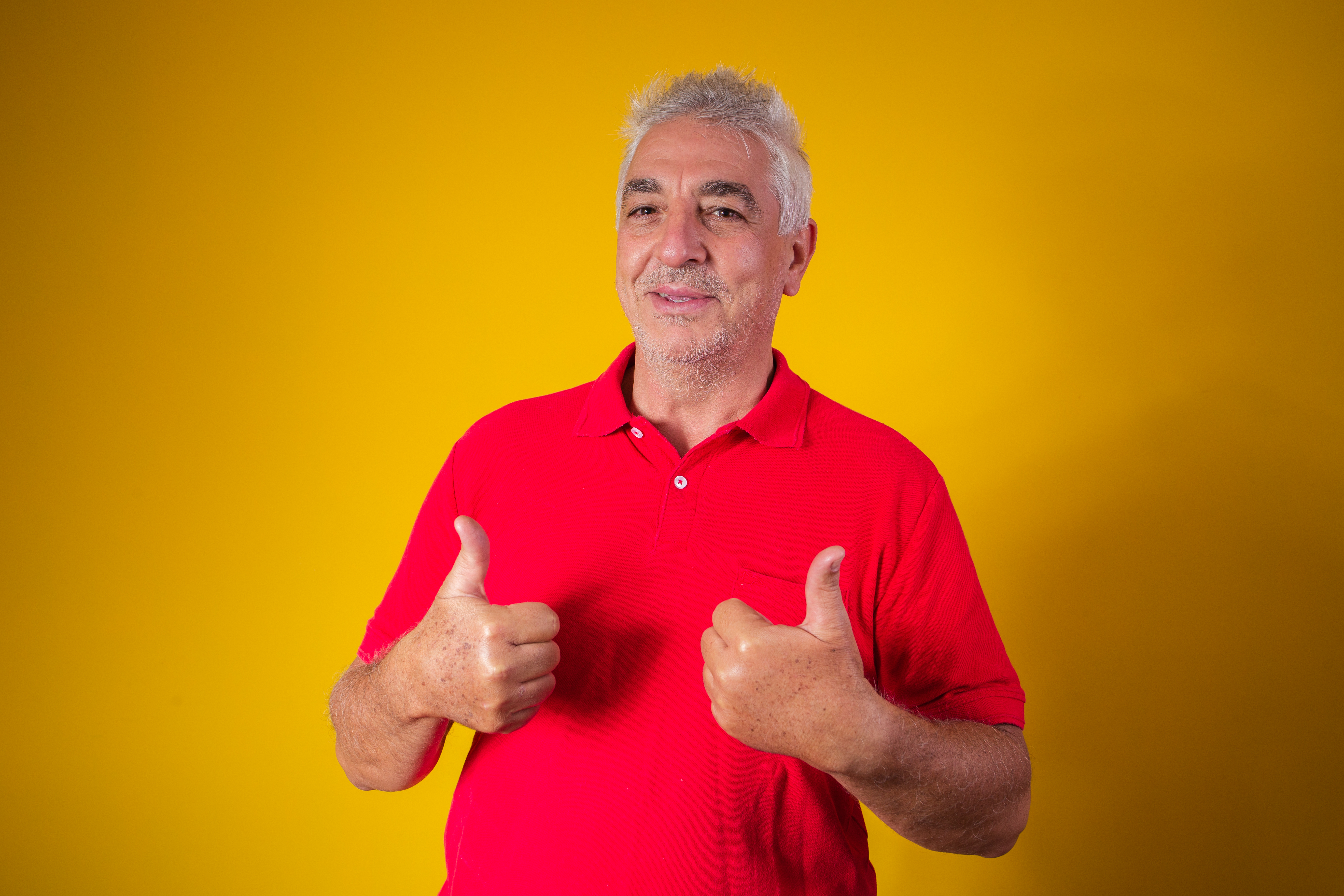 Homem idoso com camisa vermelha em fundo amarelo