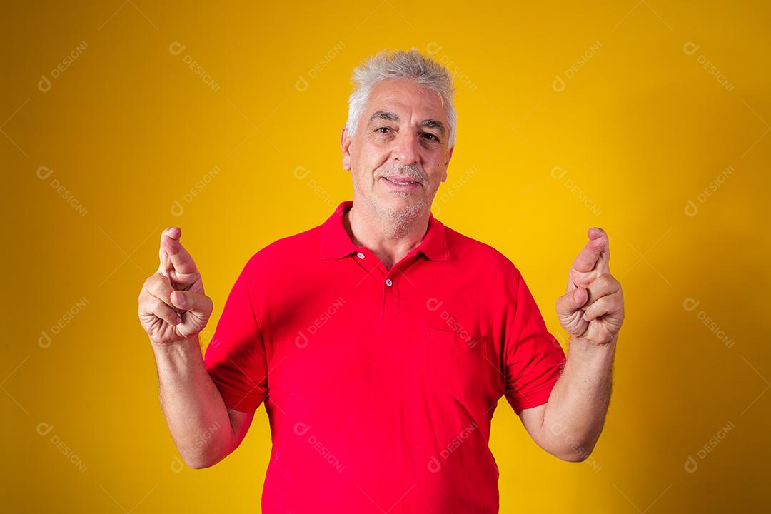 Homem idoso com camisa vermelha em fundo amarelo