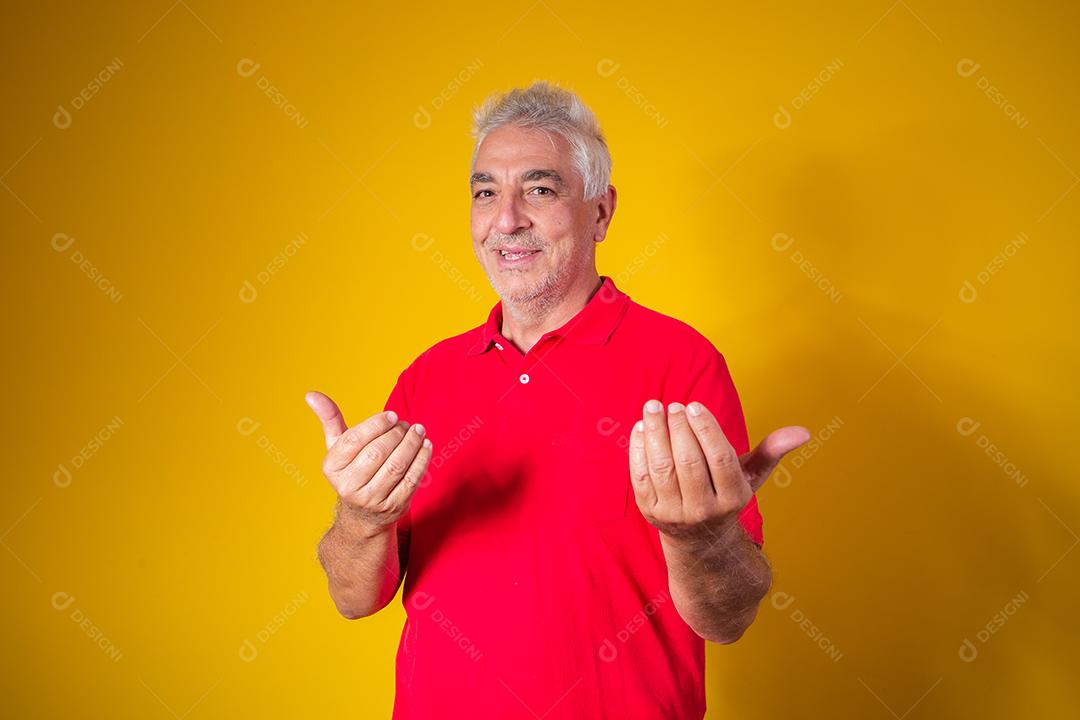 Homem idoso com camisa vermelha em fundo amarelo