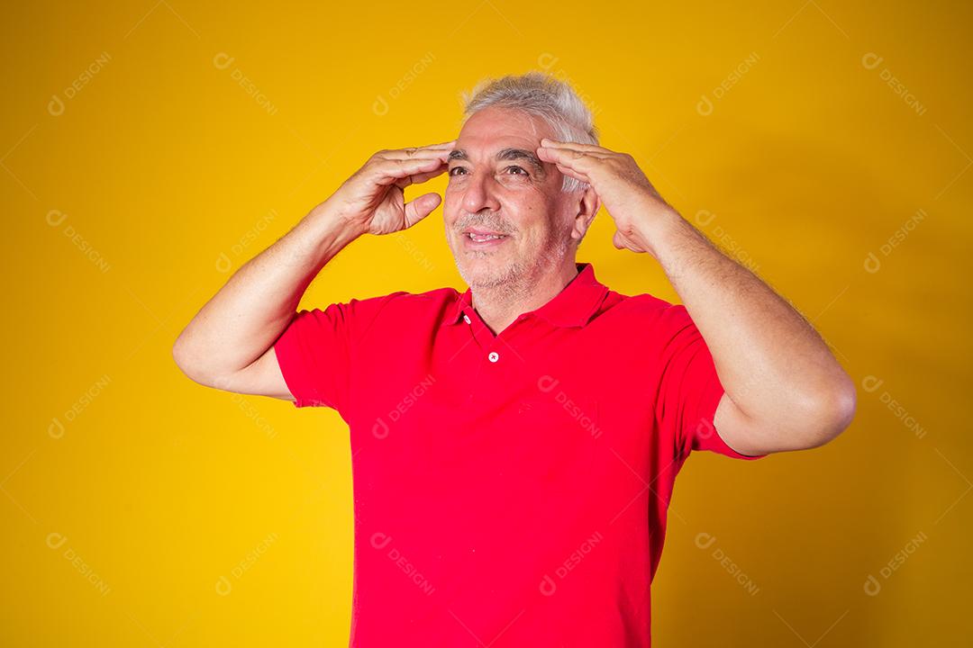 Homem idoso com camisa vermelha em fundo amarelo