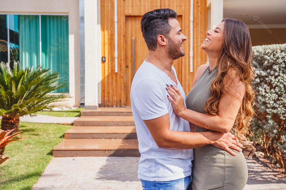 Casal abraçados em frente de casa felizes Imagem