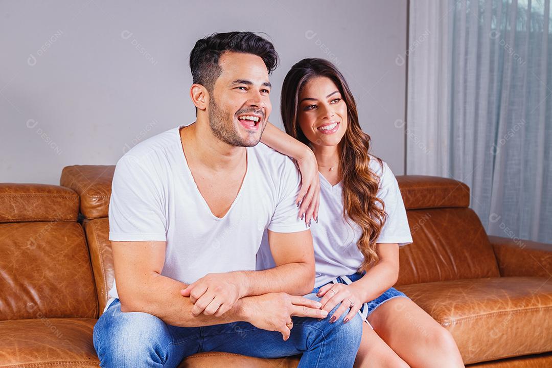 Homem sentado no sofá de casa segurando celular