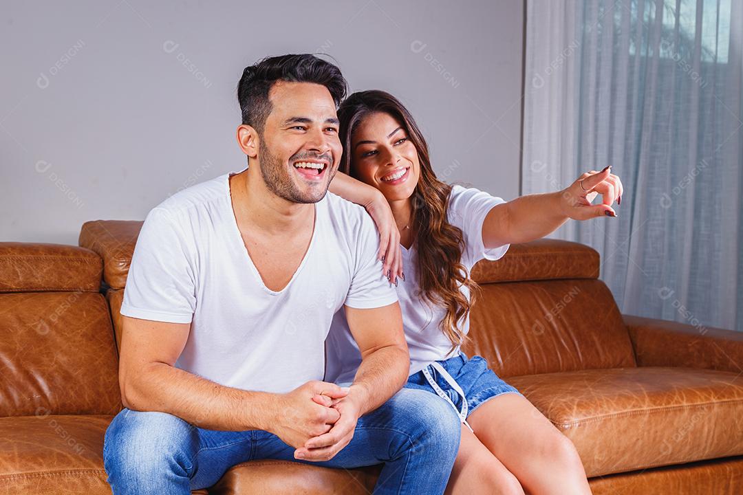 Homem e mulher sentado no sofá de casa assistindo tv