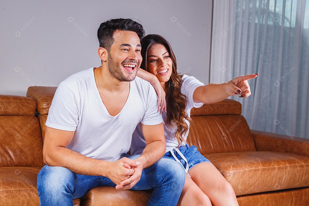Homem e mulher assistindo tv sentados em sofá