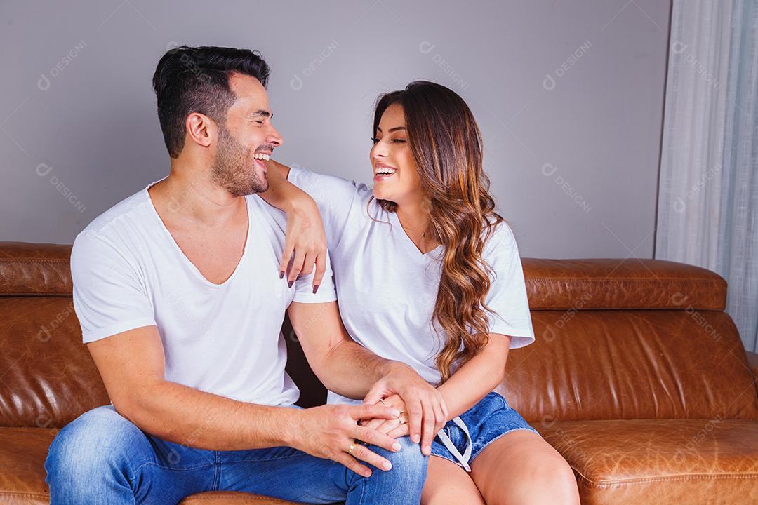 Homem e mulher sentado no sofá de casa assistindo tv