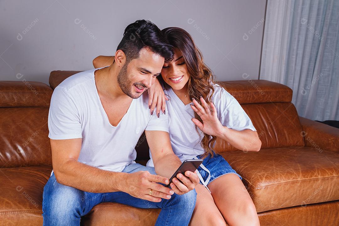 Homem e mulher sentado no sofá de casa assistindo tv