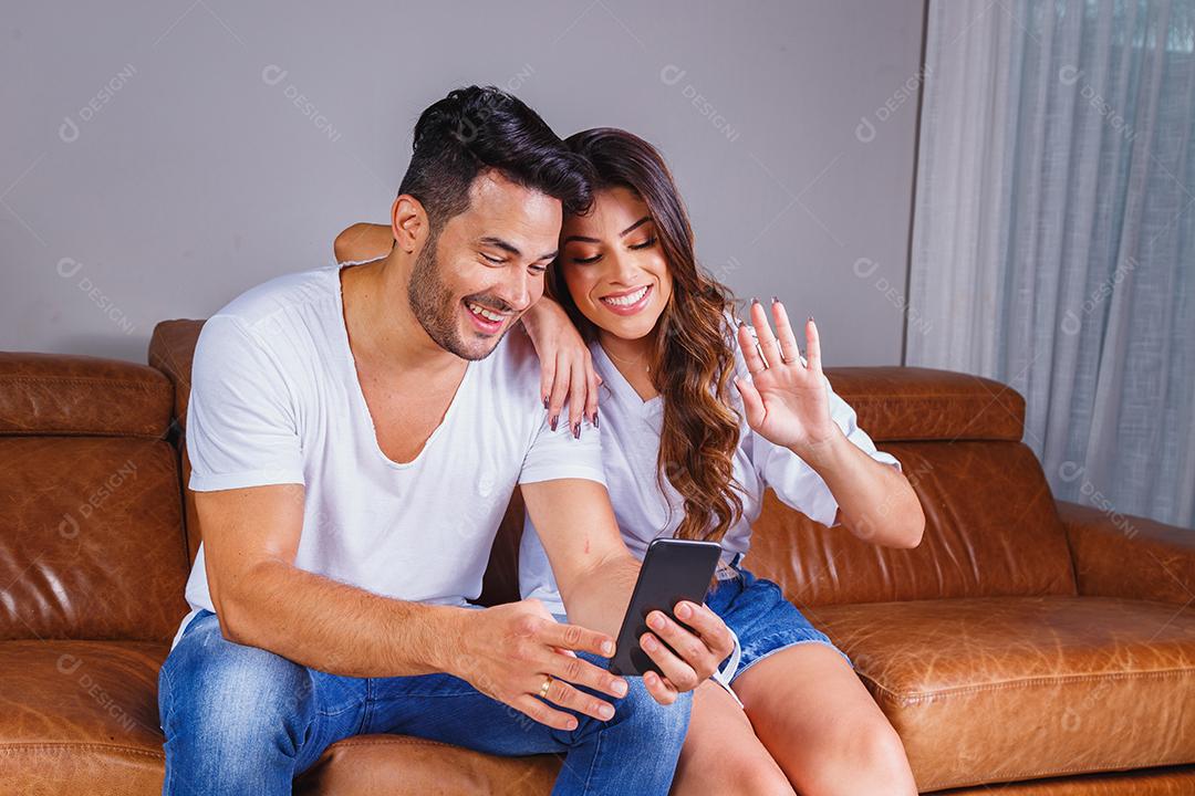 Homem e mulher sentado no sofá de casa assistindo tv