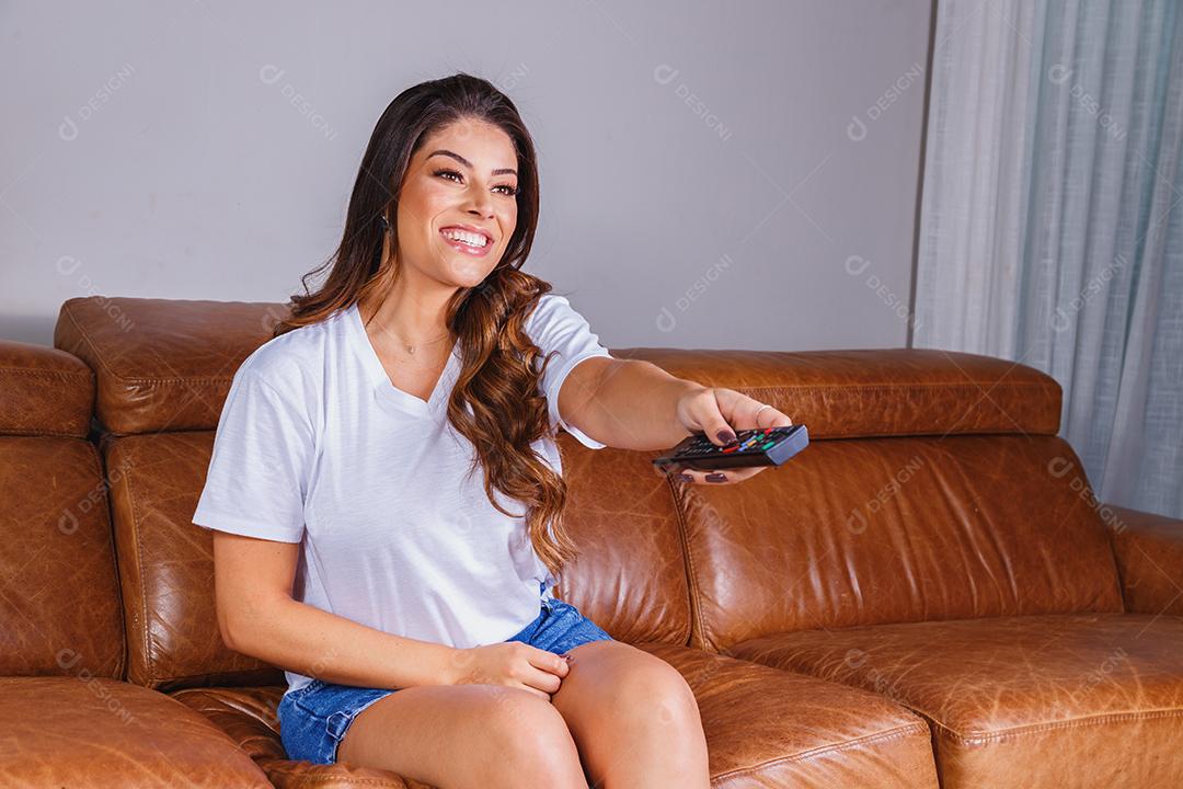 Mulher sentado no sofá de casa assistindo tv