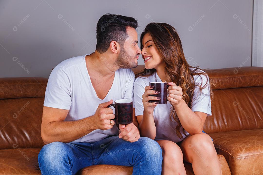 Homem e mulher casal sentado no sofá de casa assistindo tv