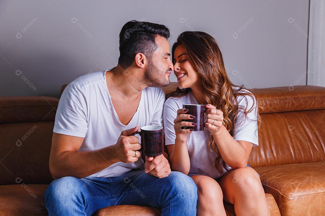 Homem e mulher casal sentado no sofá de casa assistindo tv
