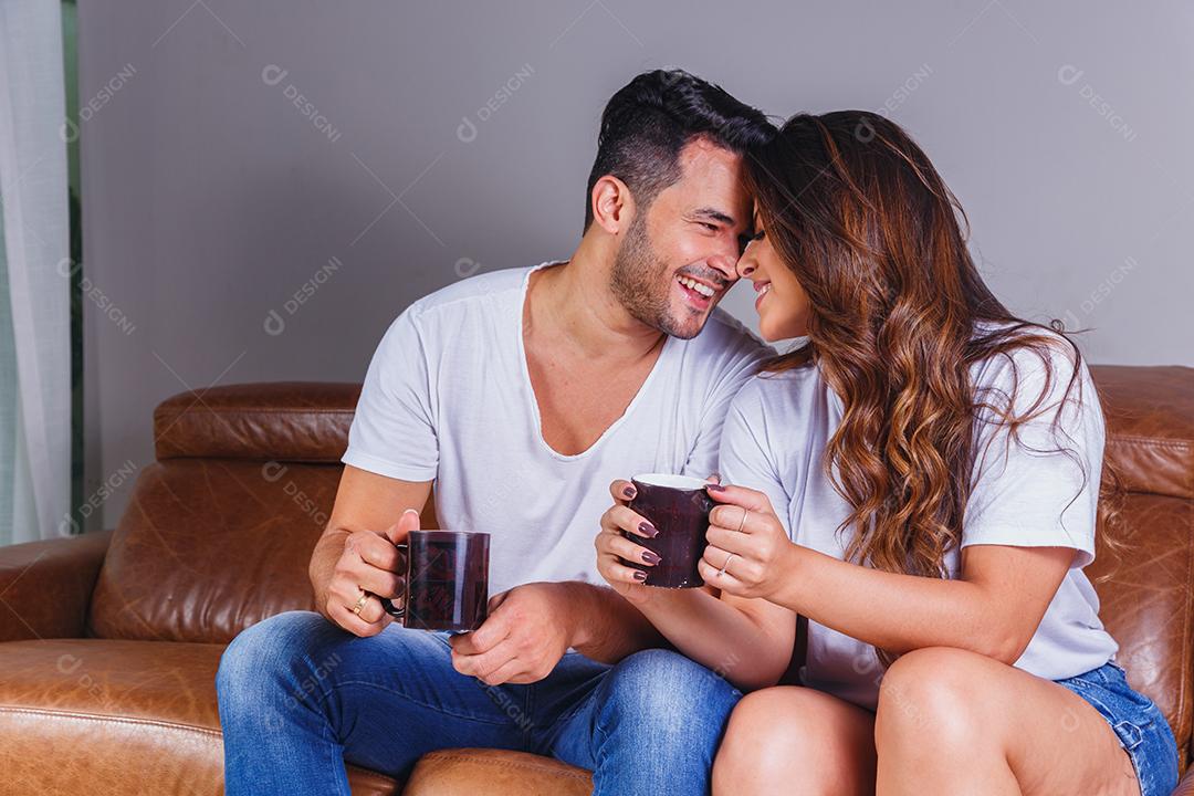 Homem e mulher casal sentado no sofá de casa assistindo tv