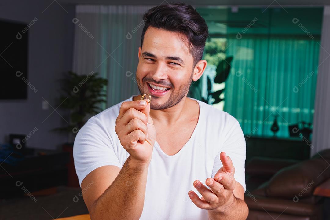 Homem segurando aliança de casamento dentro de casa