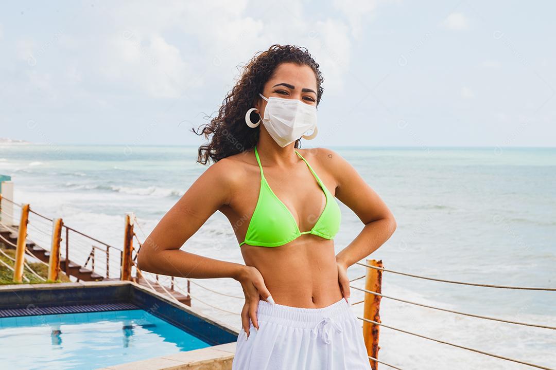 Mulher usando máscara médica na praia, novas regras normais, banner da web. Vida após pandemia, uso obrigatório de máscara facial