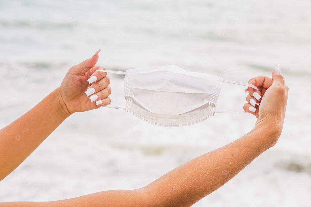 Mulher em cima de ponte de biquini verde ao lado de mar segurando mascara