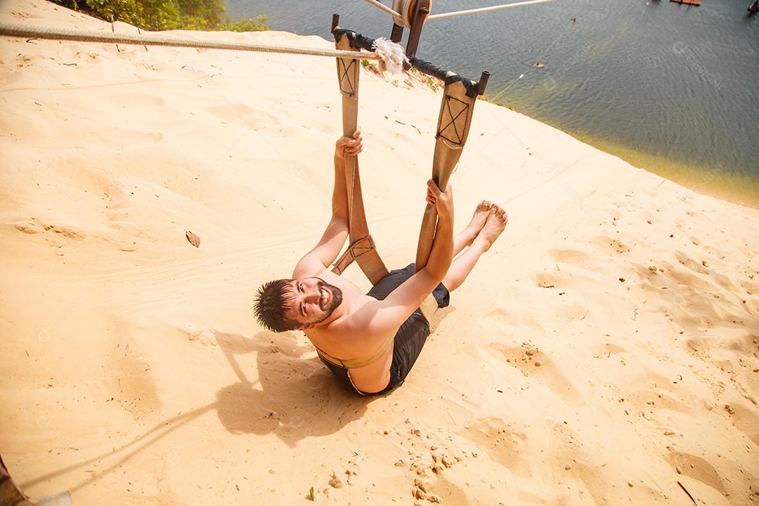 homem sentado de costas e olhando de lado em uma tirolesa com vista para a Lagoa de Jacomã na cidade de Natal -RN