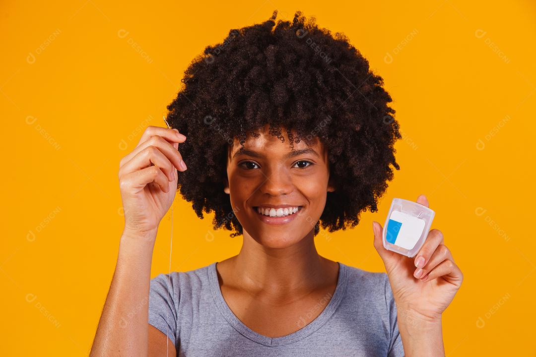 mulher afro passando fio dental nos dentes. conceito de saúde bucal